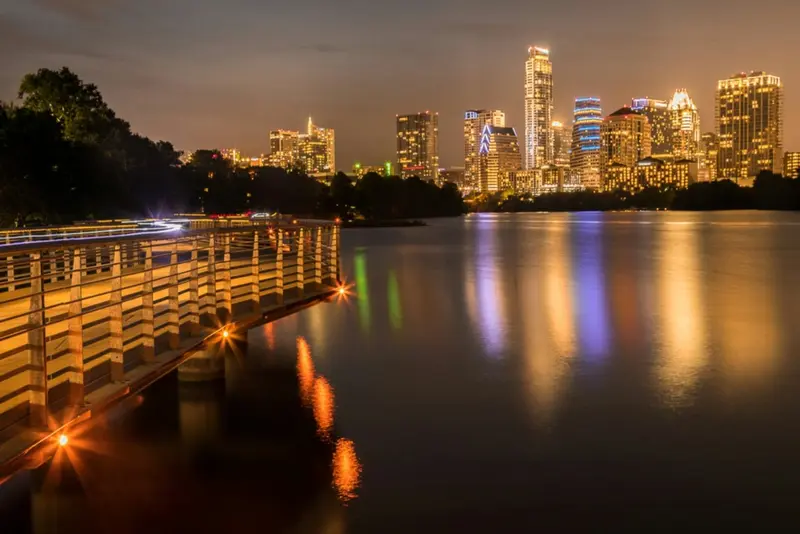 A landscape of Austin Texas river and skyscrapers at night.